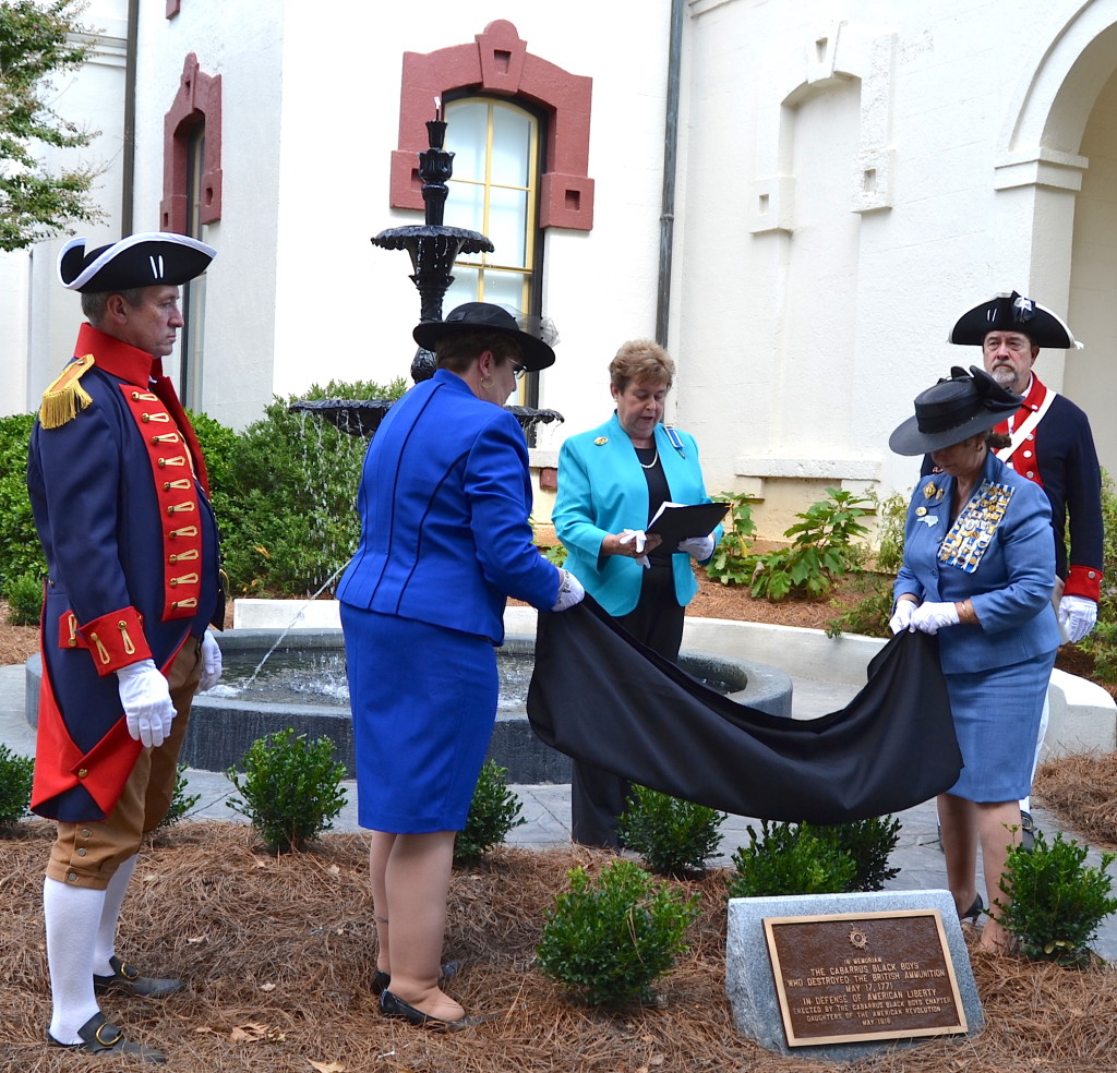 Mecklenburg SAR members Dave Alls, at left, and Ken Luckey, at right, assist Cabarrus Black Boys DAR chapter project chairs Louis Marlow and Deloris Clodfelter with the unveiling ceremony.